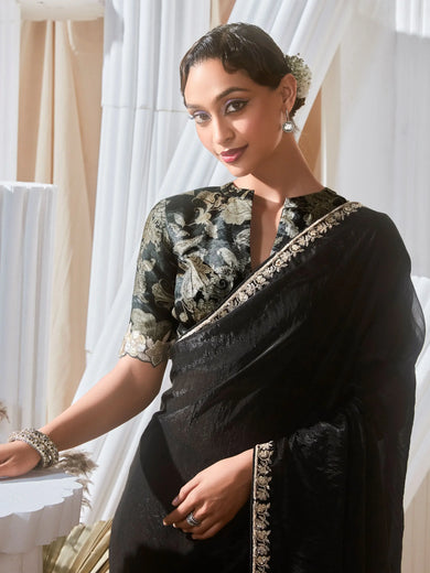 Woman wearing a black saree with a floral blouse